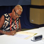 Margaret Sivers signing the Multilateral Competent Authority Agreement